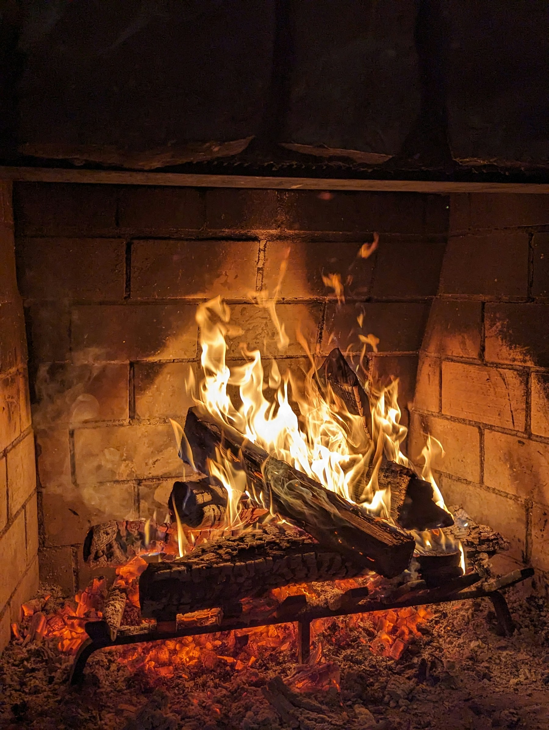 Flames curling around logs in a brick fireplace