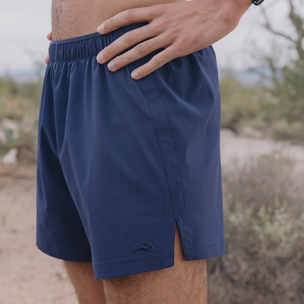 Man wearing current navy Tracksmith Twilight woven shorts in original brand photography