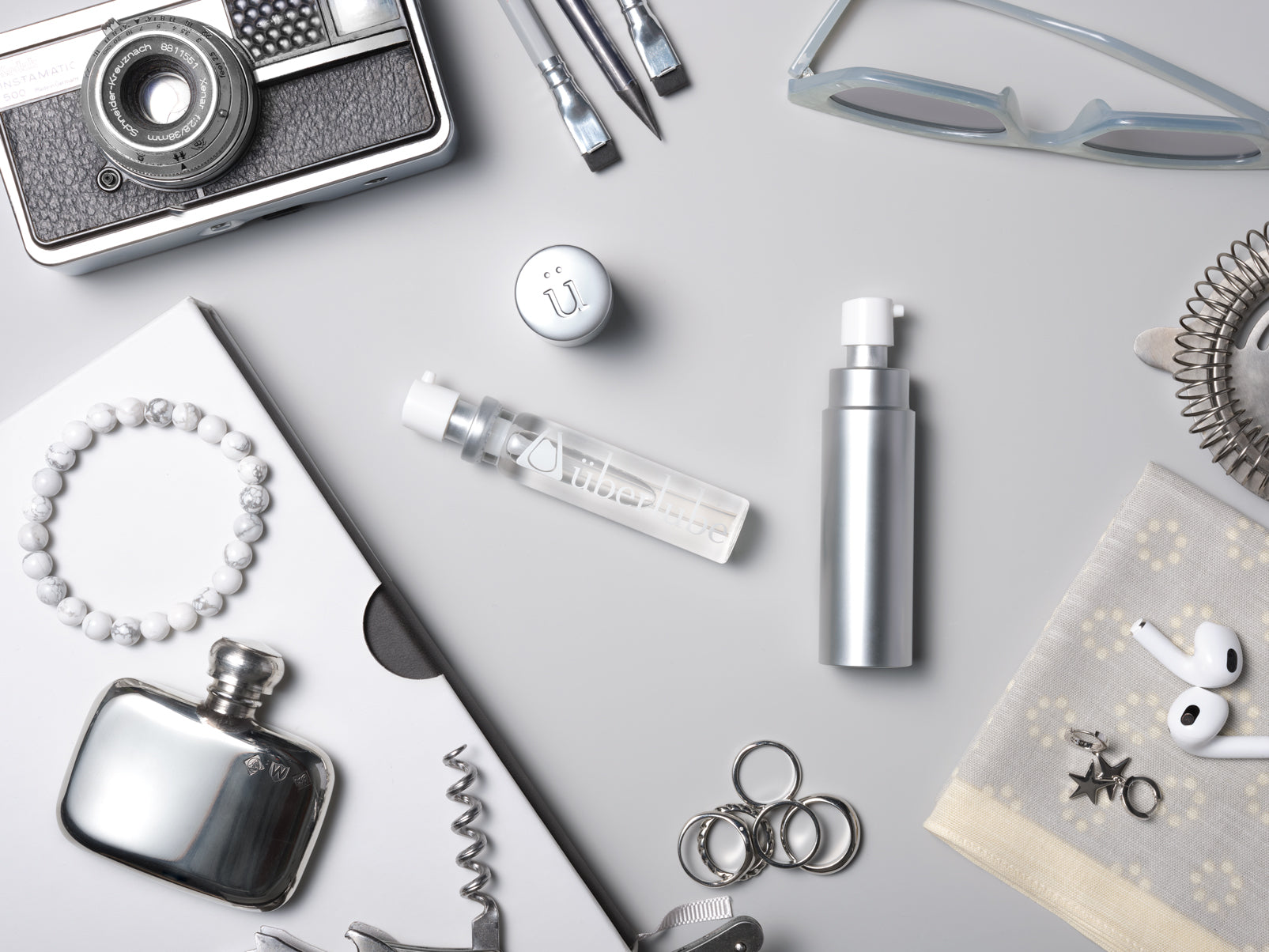 Silver Uberlube travel case and 15ml cartridge in an original travel still life