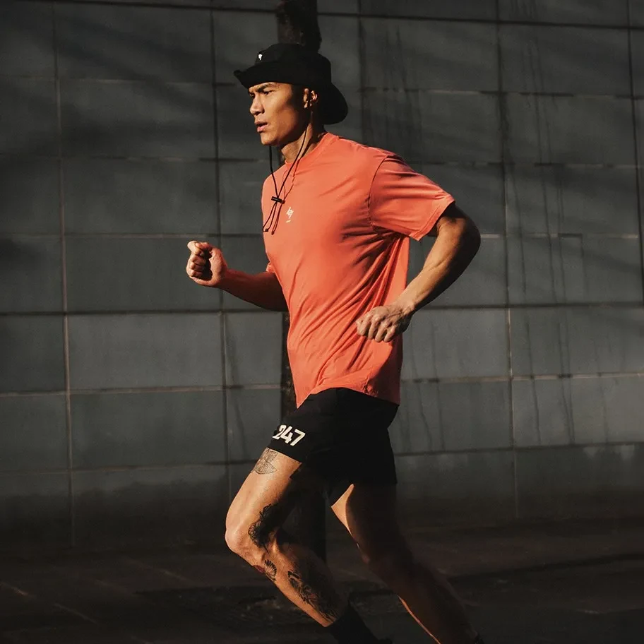 Runner wearing black Represent 247 shorts and a rust-orange T-shirt.